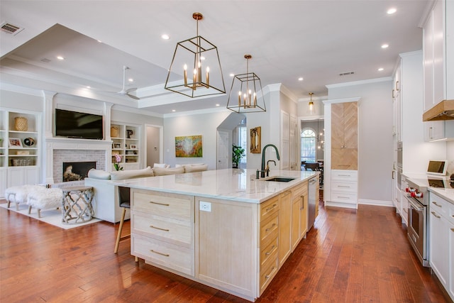 kitchen with visible vents, a sink, open floor plan, ornamental molding, and stainless steel appliances