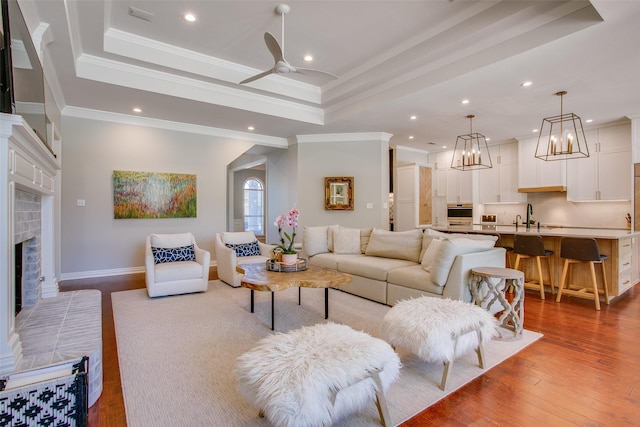 living room with a brick fireplace, recessed lighting, and a raised ceiling