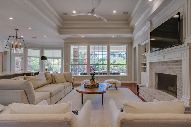 living room with crown molding, plenty of natural light, a fireplace, and wood finished floors