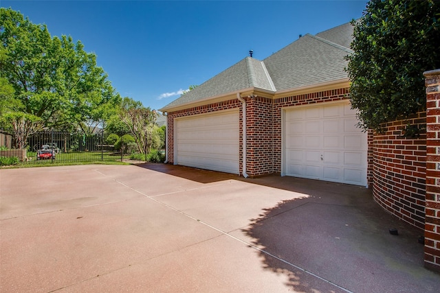 garage featuring fence and concrete driveway