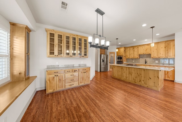 kitchen featuring stainless steel appliances, light brown cabinets, a center island, visible vents, and wood finished floors