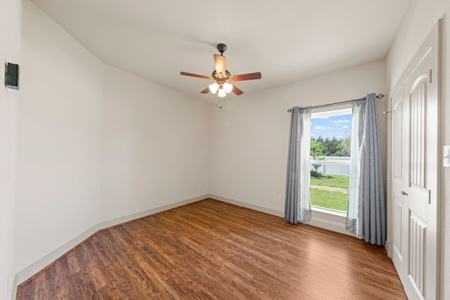 empty room featuring a ceiling fan, wood finished floors, and baseboards