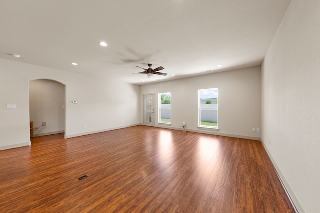 unfurnished room featuring recessed lighting, arched walkways, wood finished floors, ceiling fan, and baseboards