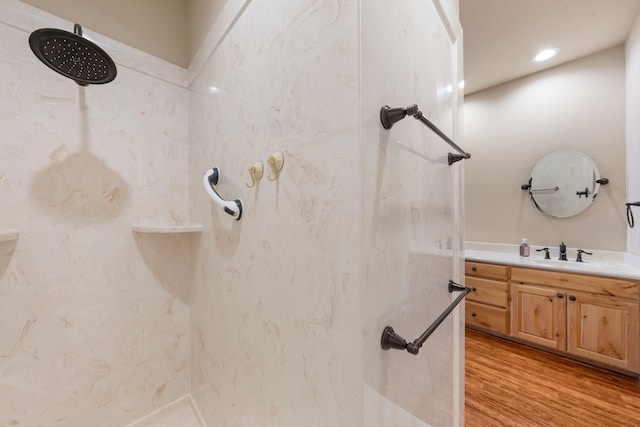 full bath with recessed lighting, wood finished floors, a marble finish shower, and vanity