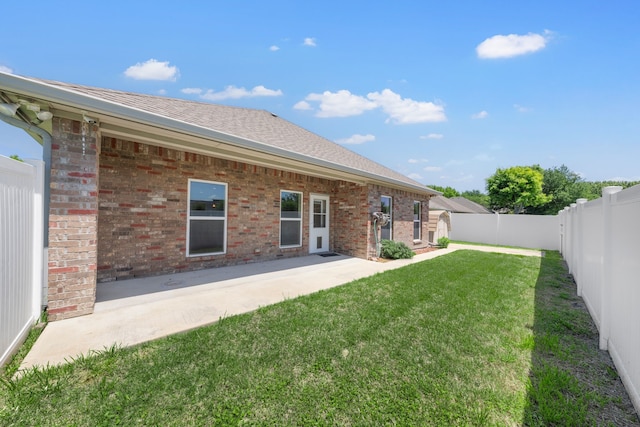 rear view of house with a lawn, a patio area, brick siding, and a fenced backyard