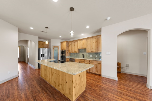 kitchen with recessed lighting, stainless steel appliances, a kitchen island, arched walkways, and dark wood finished floors