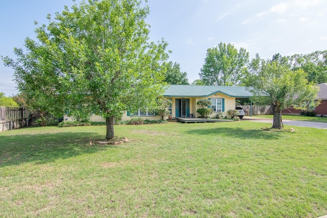 ranch-style home with fence, aphalt driveway, metal roof, an attached carport, and a front yard
