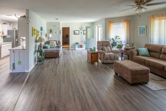 living area with ceiling fan, wood finished floors, and a healthy amount of sunlight
