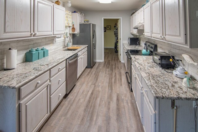 kitchen with a sink, appliances with stainless steel finishes, under cabinet range hood, and tasteful backsplash