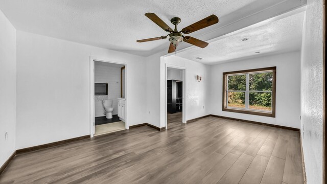 760 College Farm, Stephenville, TX 76401 - unfurnished bedroom with baseboards, wood finished floors, a textured ceiling, and ensuite bathroom