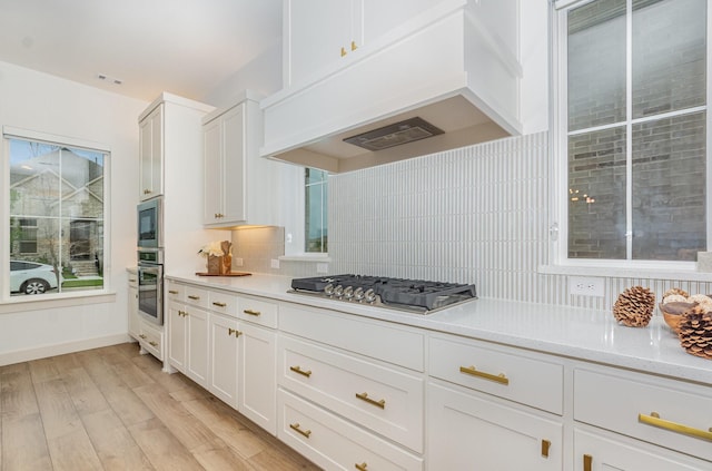 kitchen with premium range hood, light countertops, white cabinetry, backsplash, and stainless steel appliances