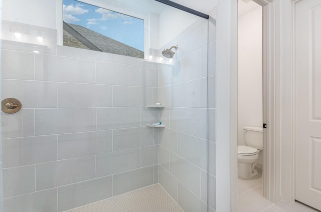 bathroom featuring toilet, tile patterned floors, and tiled shower