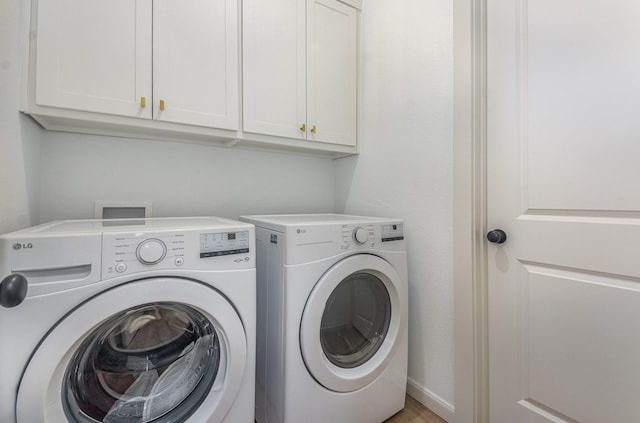 washroom featuring cabinet space and washer and clothes dryer