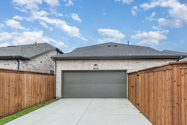 garage with fence and concrete driveway