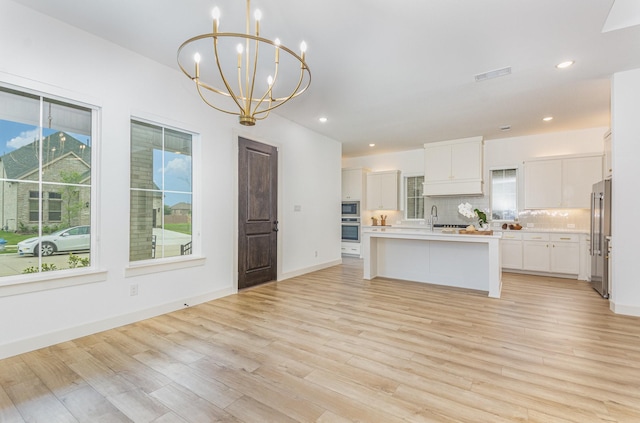 kitchen featuring a chandelier, appliances with stainless steel finishes, a wealth of natural light, and light wood finished floors
