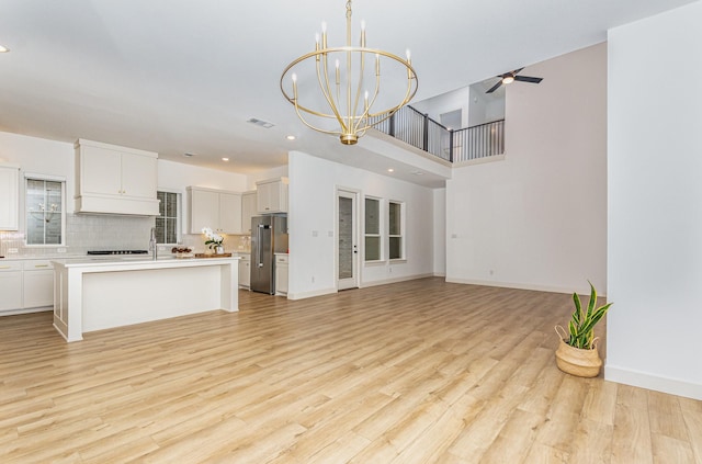 unfurnished living room with recessed lighting, ceiling fan with notable chandelier, and light wood-type flooring