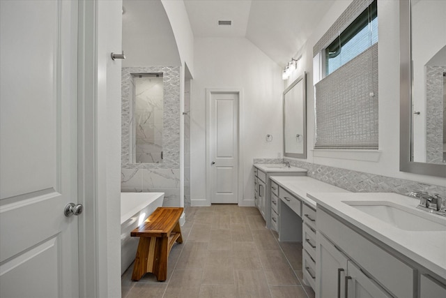 bathroom featuring a sink, double vanity, visible vents, vaulted ceiling, and a freestanding bath