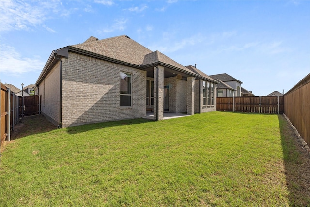 rear view of property featuring a patio, a yard, a fenced backyard, and brick siding