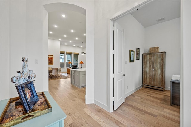 corridor with recessed lighting, arched walkways, light wood-type flooring, baseboards, and visible vents
