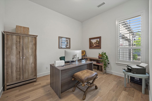 home office featuring light wood finished floors, visible vents, and baseboards