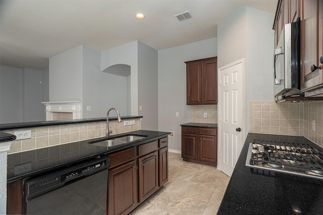 kitchen with dark stone countertops, tasteful backsplash, appliances with stainless steel finishes, a sink, and visible vents