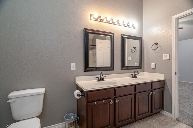 full bath featuring toilet, double vanity, and a sink