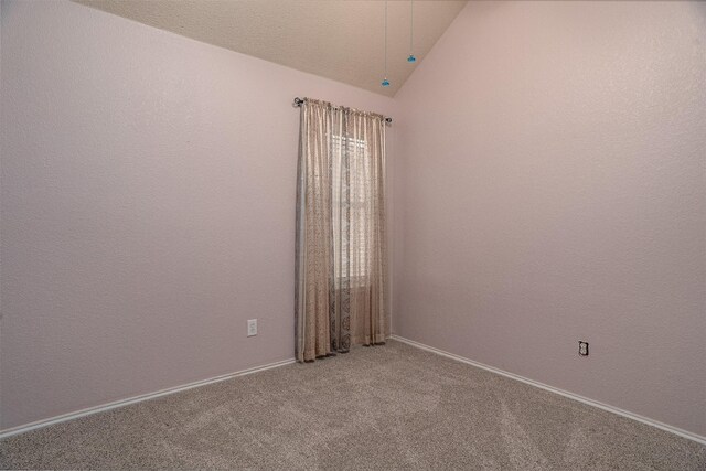 empty room featuring baseboards, lofted ceiling, and carpet