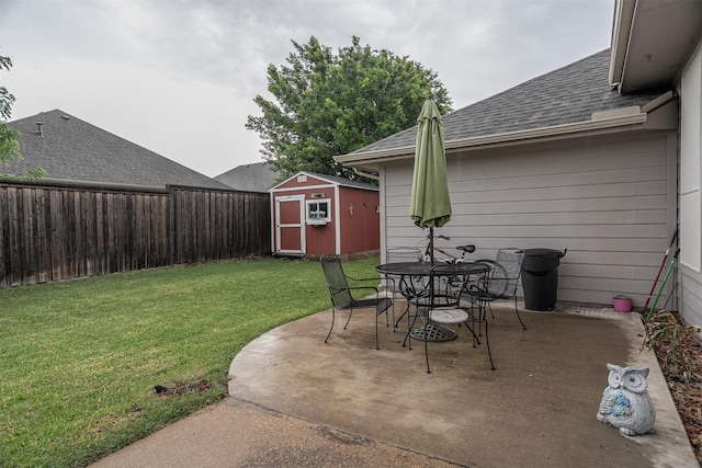 view of patio / terrace with an outbuilding, outdoor dining space, a storage unit, and a fenced backyard