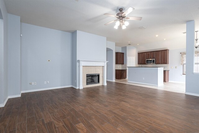 unfurnished living room featuring recessed lighting, a tiled fireplace, a ceiling fan, baseboards, and wood finished floors