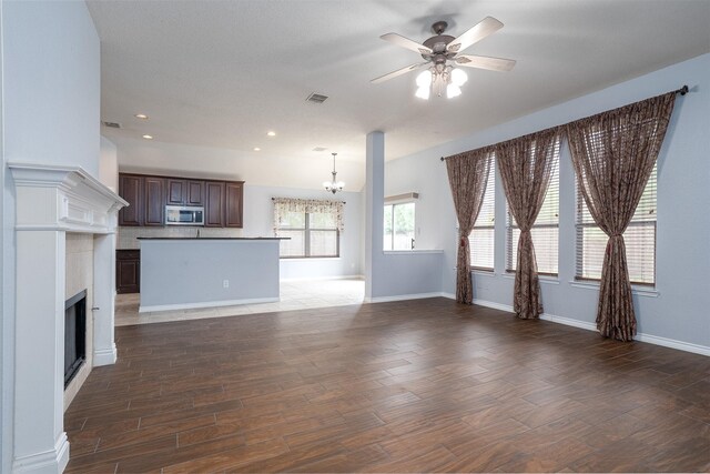 unfurnished living room featuring recessed lighting, wood finished floors, ceiling fan with notable chandelier, and a fireplace