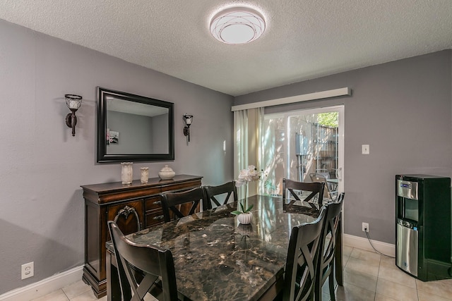 dining area featuring light tile patterned flooring, a textured ceiling, and baseboards