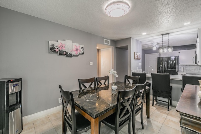 dining room featuring ceiling fan, baseboards, visible vents, a textured ceiling, and light tile patterned flooring