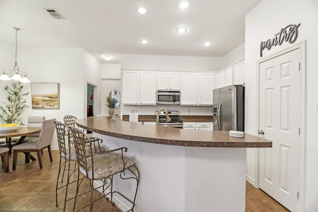 kitchen with visible vents, tile patterned flooring, dark countertops, a breakfast bar area, and appliances with stainless steel finishes