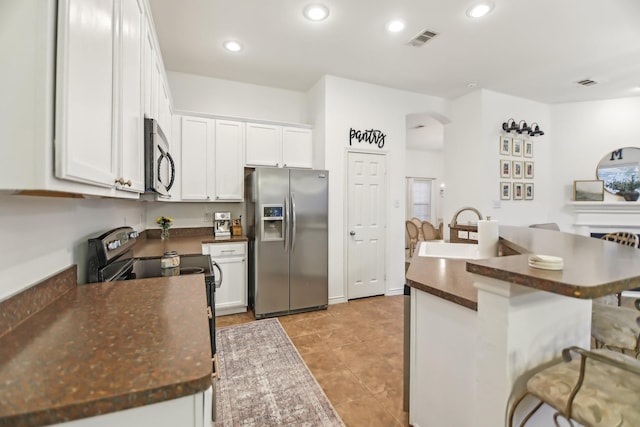 kitchen featuring visible vents, dark countertops, arched walkways, a sink, and stainless steel appliances
