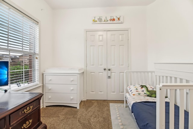 carpeted bedroom featuring a nursery area and a closet
