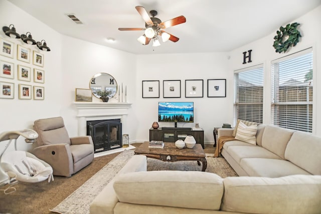 carpeted living room featuring visible vents, a ceiling fan, a fireplace with flush hearth, and baseboards