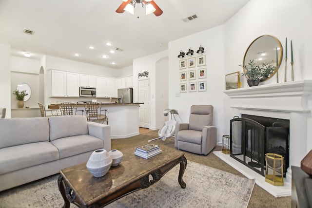 living room with arched walkways, carpet, a ceiling fan, and visible vents