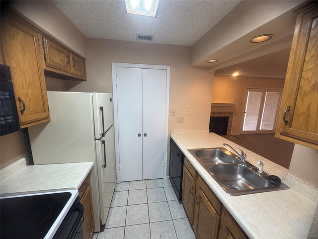 kitchen with black appliances, a textured ceiling, brown cabinets, and a sink