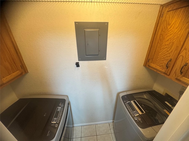 washroom featuring cabinet space, light tile patterned floors, electric panel, hookup for a washing machine, and baseboards