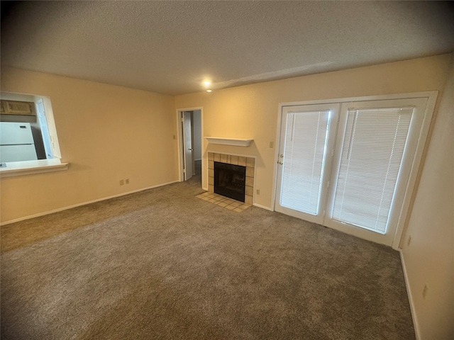 unfurnished living room featuring baseboards, a fireplace, a textured ceiling, and carpet flooring