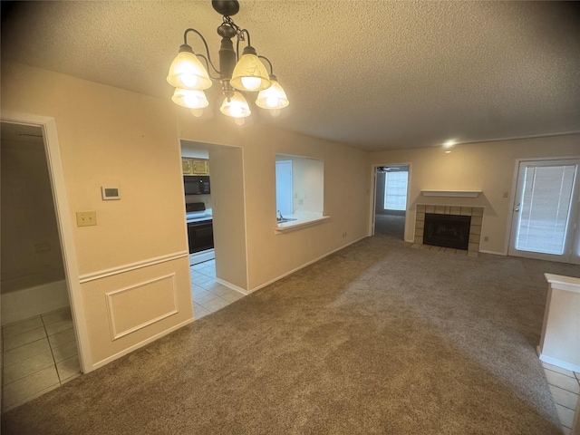 unfurnished living room with a notable chandelier, a textured ceiling, carpet, and a fireplace