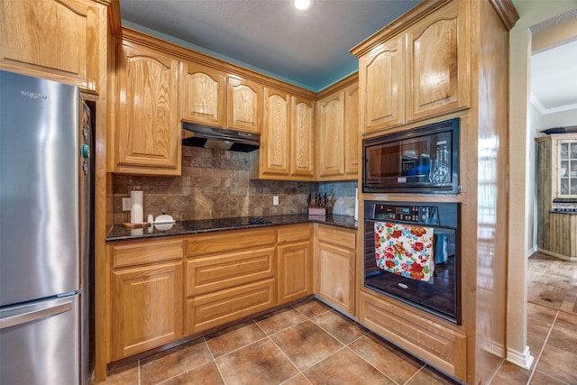 kitchen featuring under cabinet range hood, dark stone countertops, tasteful backsplash, black appliances, and ornamental molding