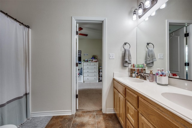 bathroom with tile patterned floors, baseboards, double vanity, and a sink