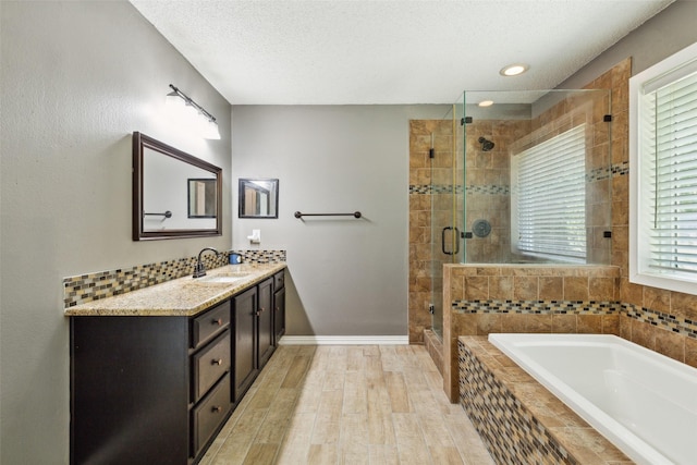 117 Carrington Dr, Fate, TX 75032 - full bathroom with a textured ceiling, a garden tub, a stall shower, wood finished floors, and vanity