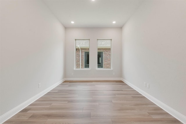 empty room with light wood-style floors, recessed lighting, and baseboards