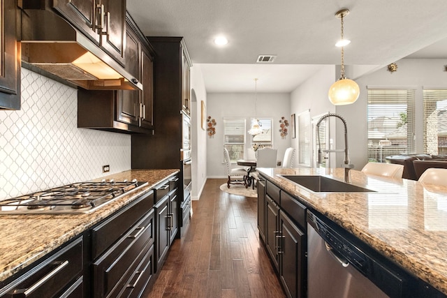 kitchen featuring light stone countertops, under cabinet range hood, appliances with stainless steel finishes, a sink, and visible vents