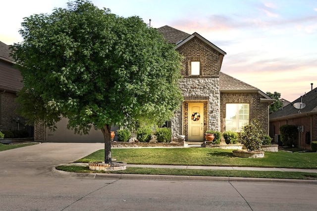 view of front of property featuring brick siding, a yard, a shingled roof, and concrete driveway