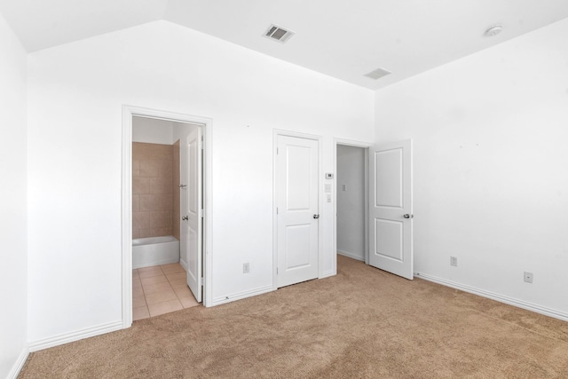 unfurnished bedroom featuring visible vents, vaulted ceiling, carpet, and baseboards