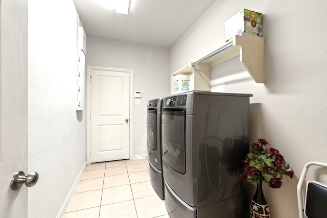 laundry room featuring baseboards, light tile patterned floors, washing machine and clothes dryer, and laundry area