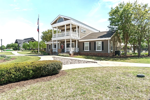 neoclassical home with a porch, a front lawn, fence, and a balcony